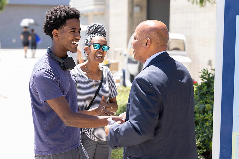 President Rochon greeting a male student with his mother.