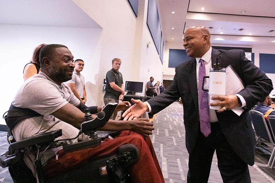 President Rochon shaking hands with a staff member seated in wheelchair.