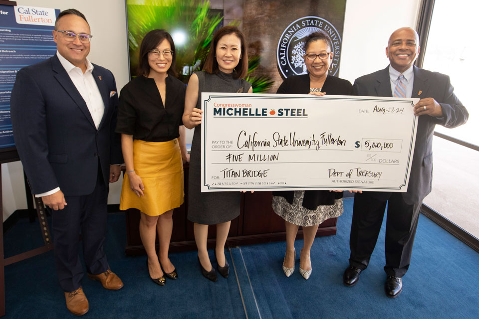 Michelle Steele and President Rochon holding up a large check.