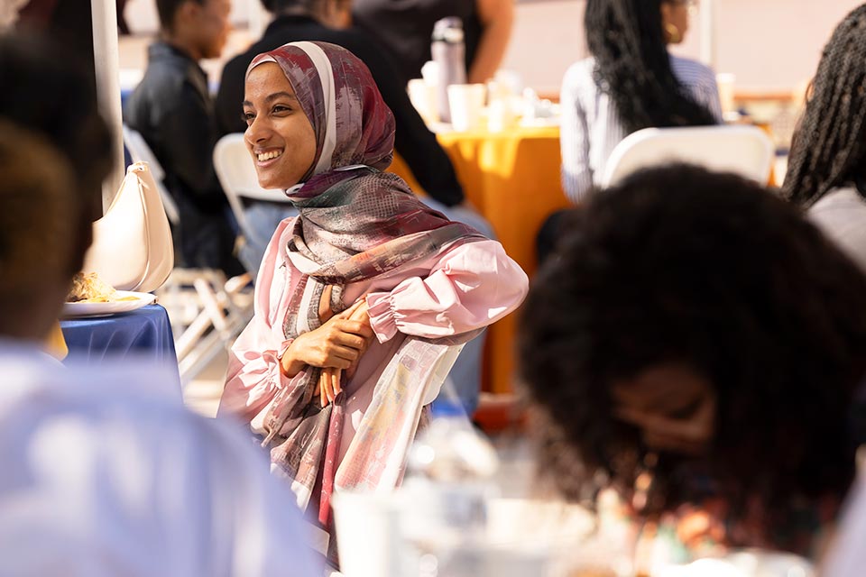 A seated attendee smiling while listening to speaker.