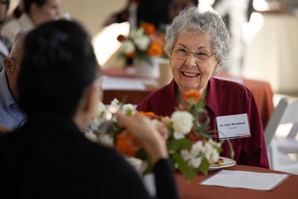 Emerita Jo Ann Woodard smiling in conversation with another person