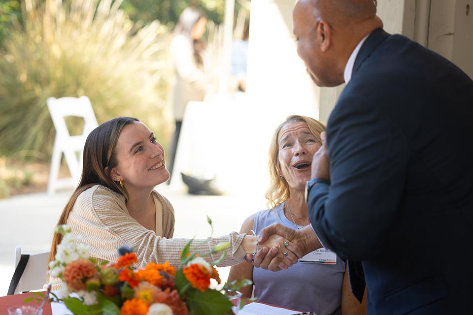 President Rochon shaking hands with student scholarship recipient while her mother express joy