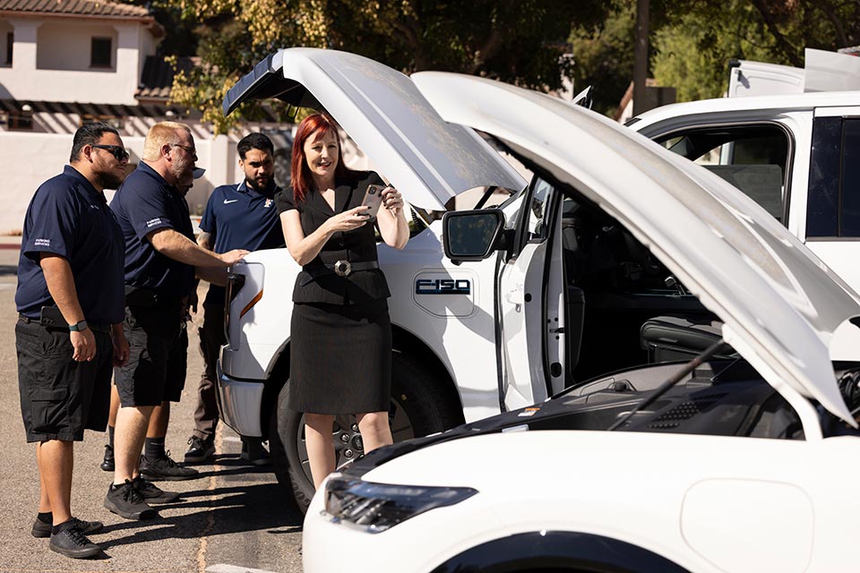 A group takes photos of exhibiting cars with hood open