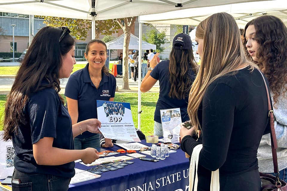 Staff member at info booth providing literature to student