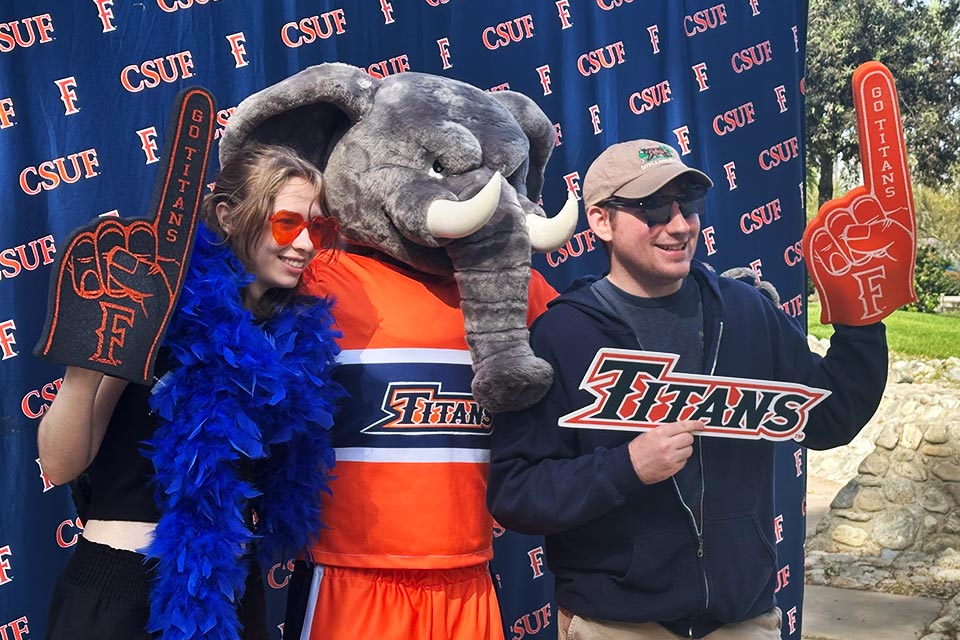 Two students posing with Tuffy and holding up swags