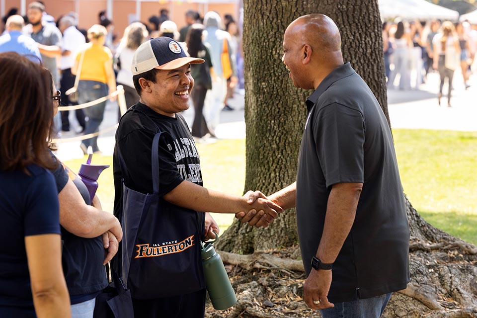 President Rochon shaking hand with a student